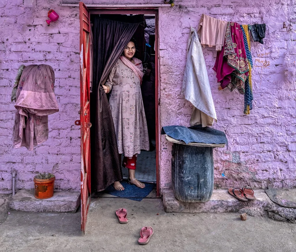 woman wearing all purple stands in the doorway of a light purple building
