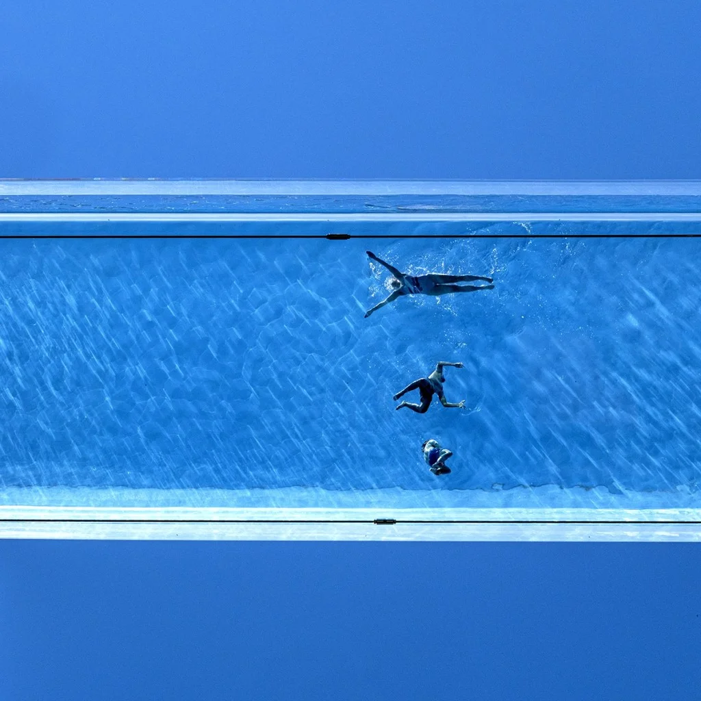 looking up at a swimming pool with three swimmers