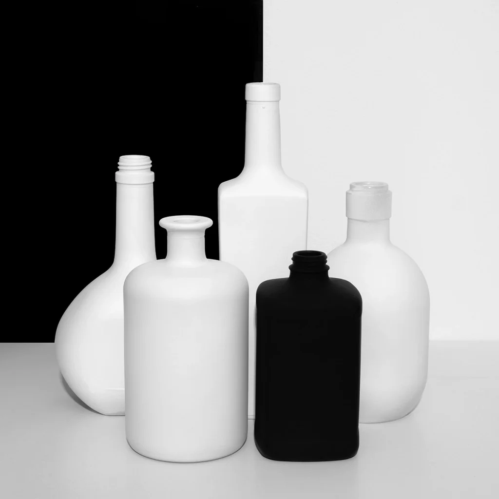 still life photo of white bottles with a black bottle in front