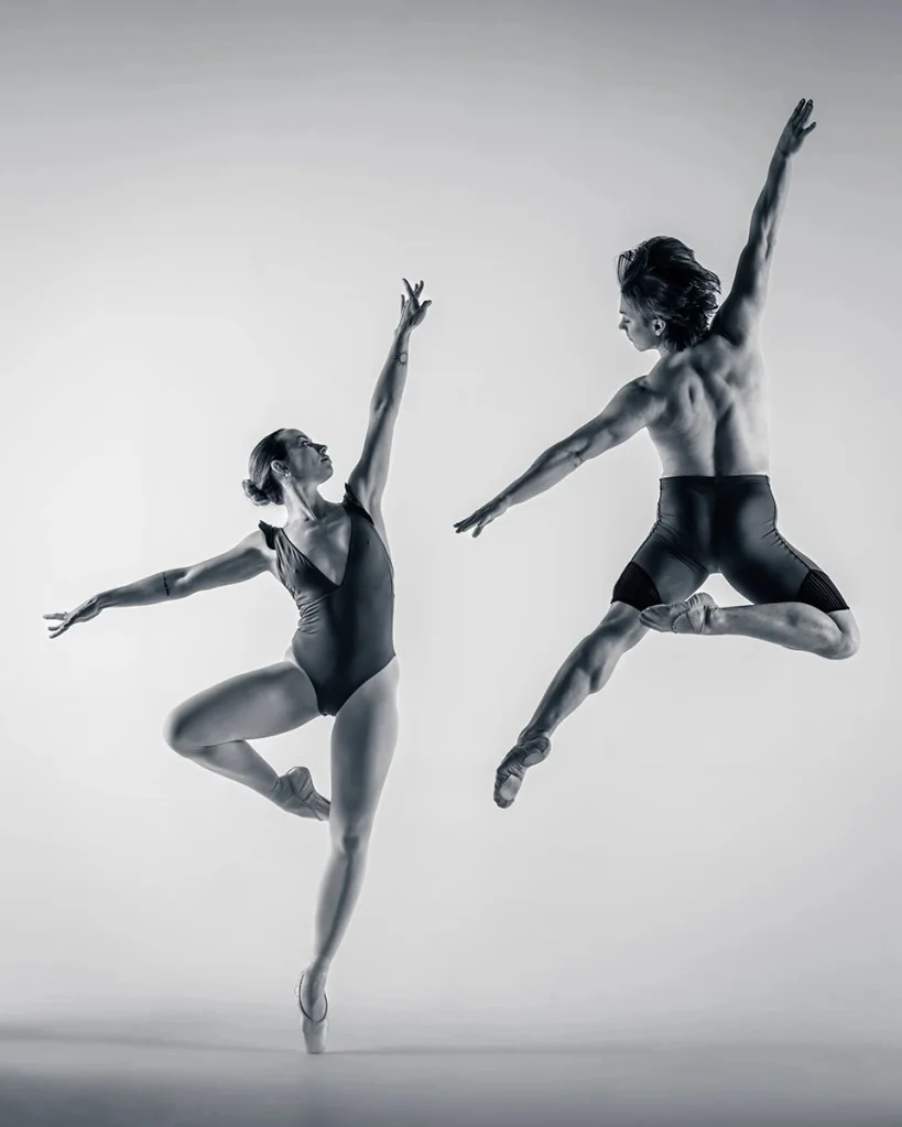 two dancers mid-air arms extended
