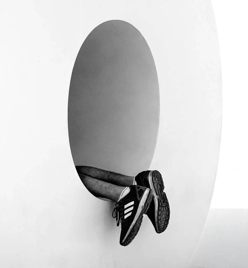 person lying in a circle shape hole, creating a Q shape with legs