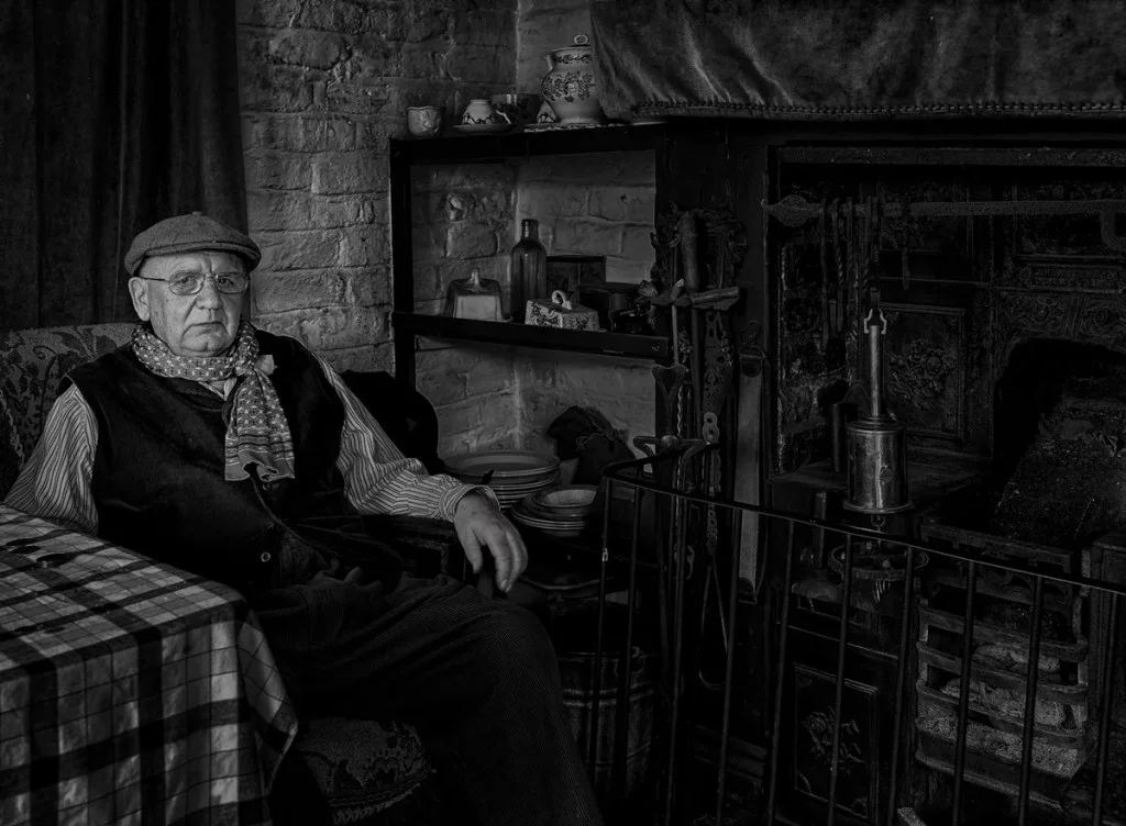 old man in a flat cap sat in an armchair