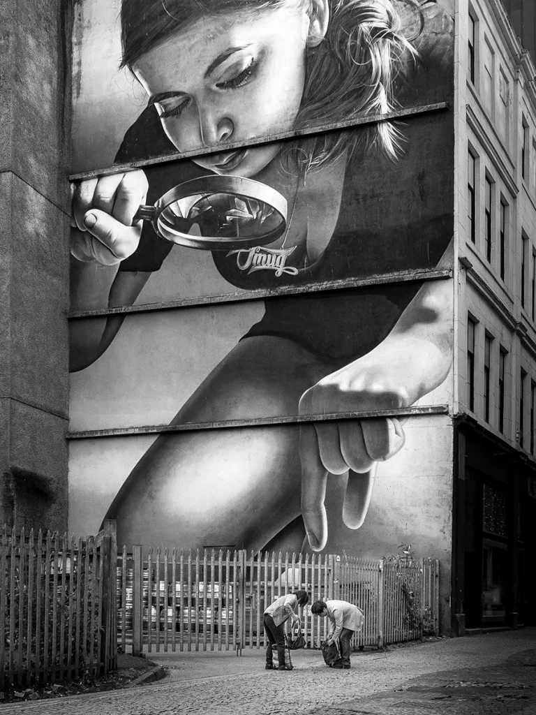 Photo of two people bending over in front of street art