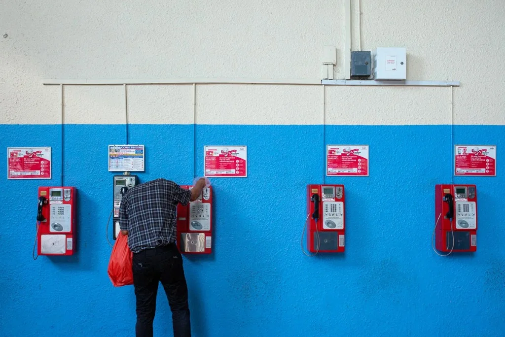 Photo of a person bent over the telephone on the wall