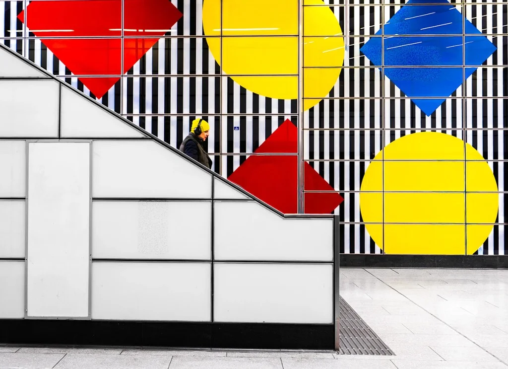Person walking down steps past stripey wall with bold colours