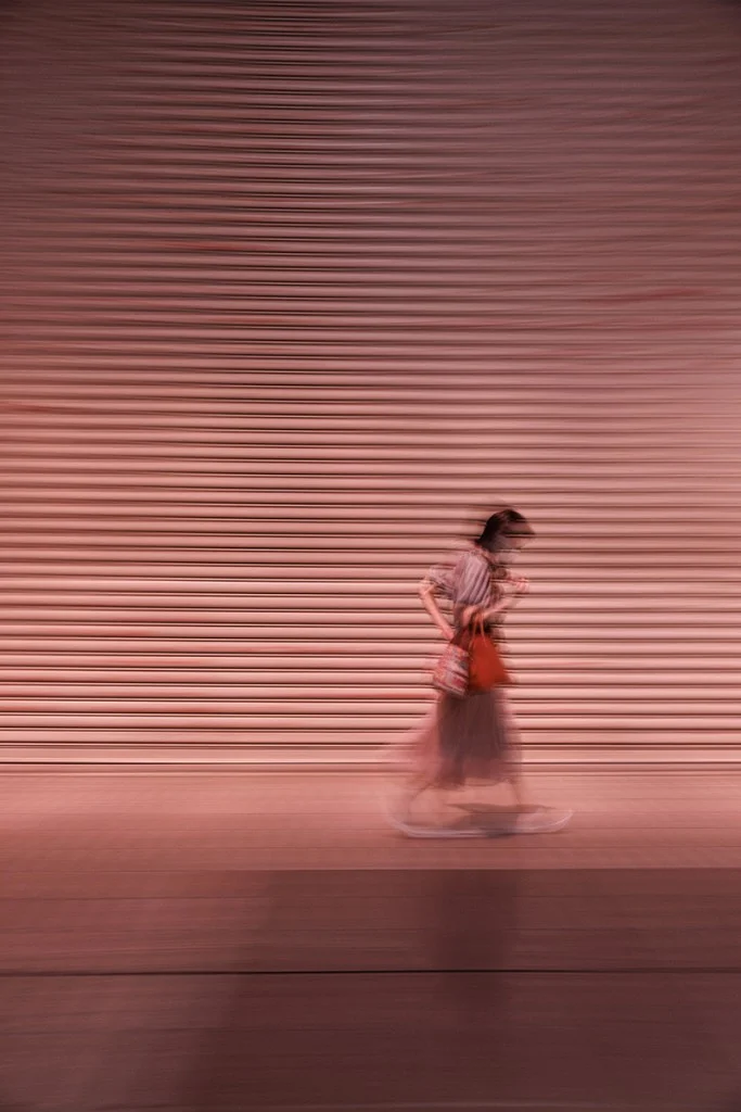 Long exposure photo of a woman walking past a building