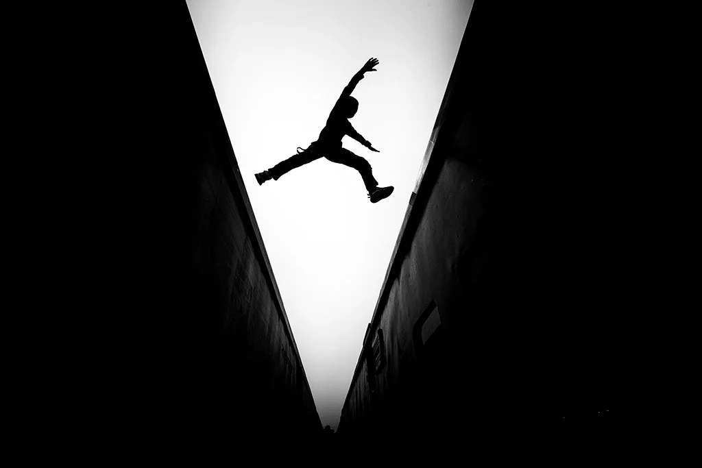 Silhouette of person leaping between two walls