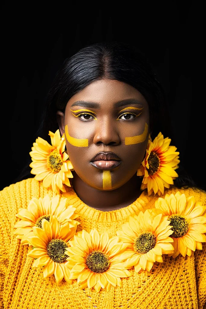 woman in yellow with yellow face markings wearing sunflower earrings and necklace