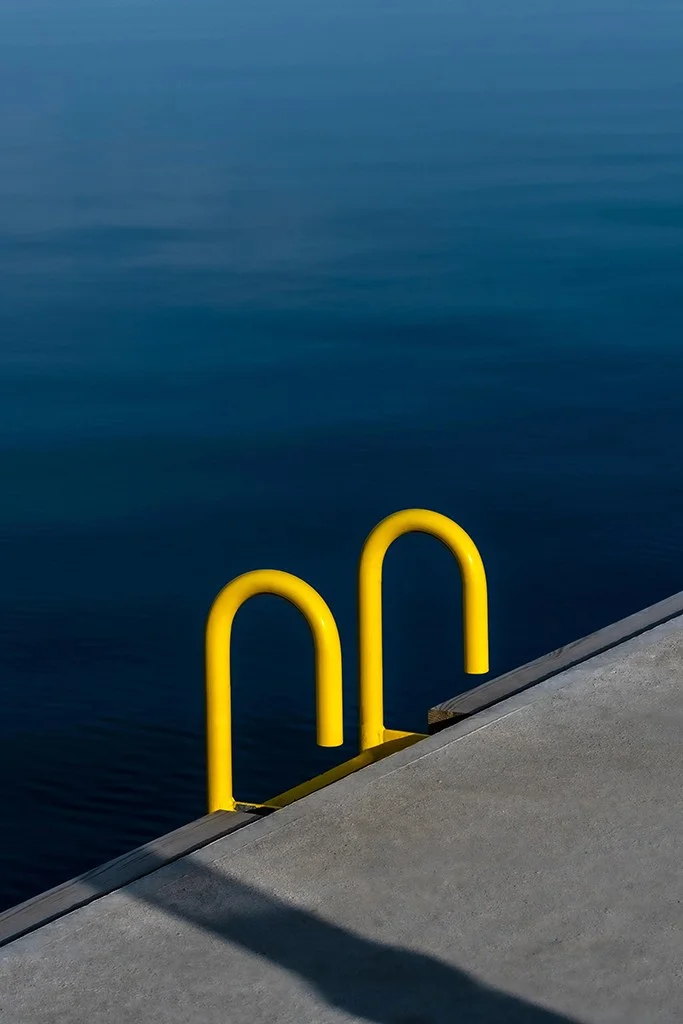 yellow step ladder arms against blue water