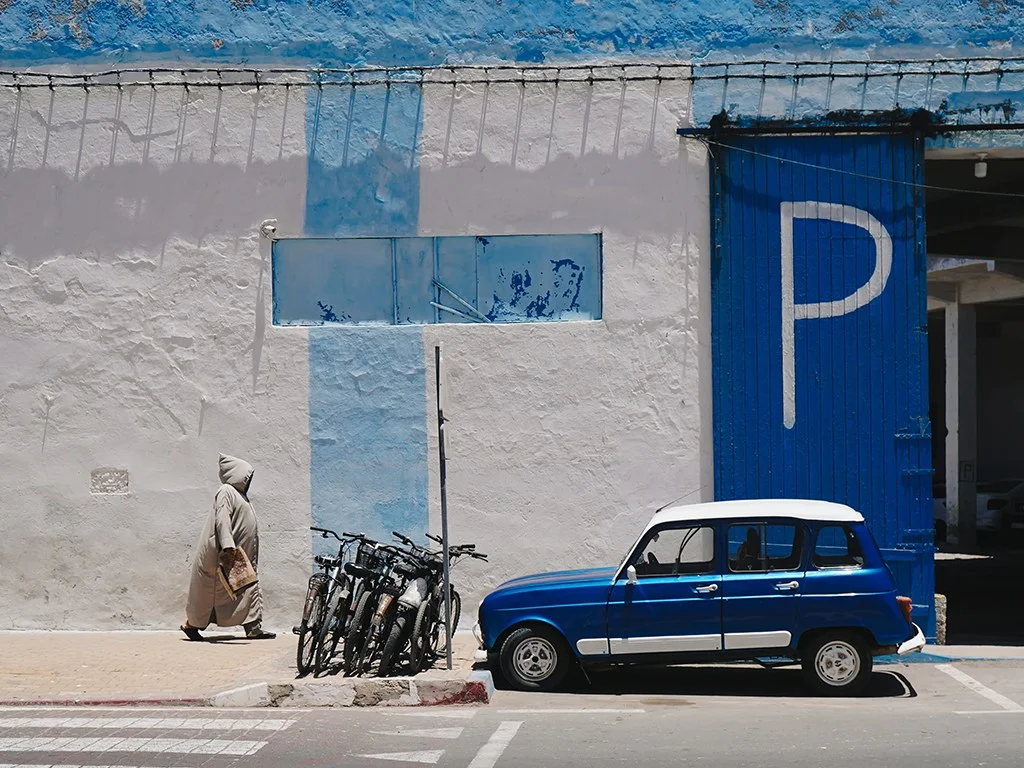 small blue car parked in front of a blue and white building