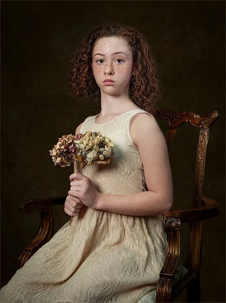 Curly-haired girl with flowers in a chair