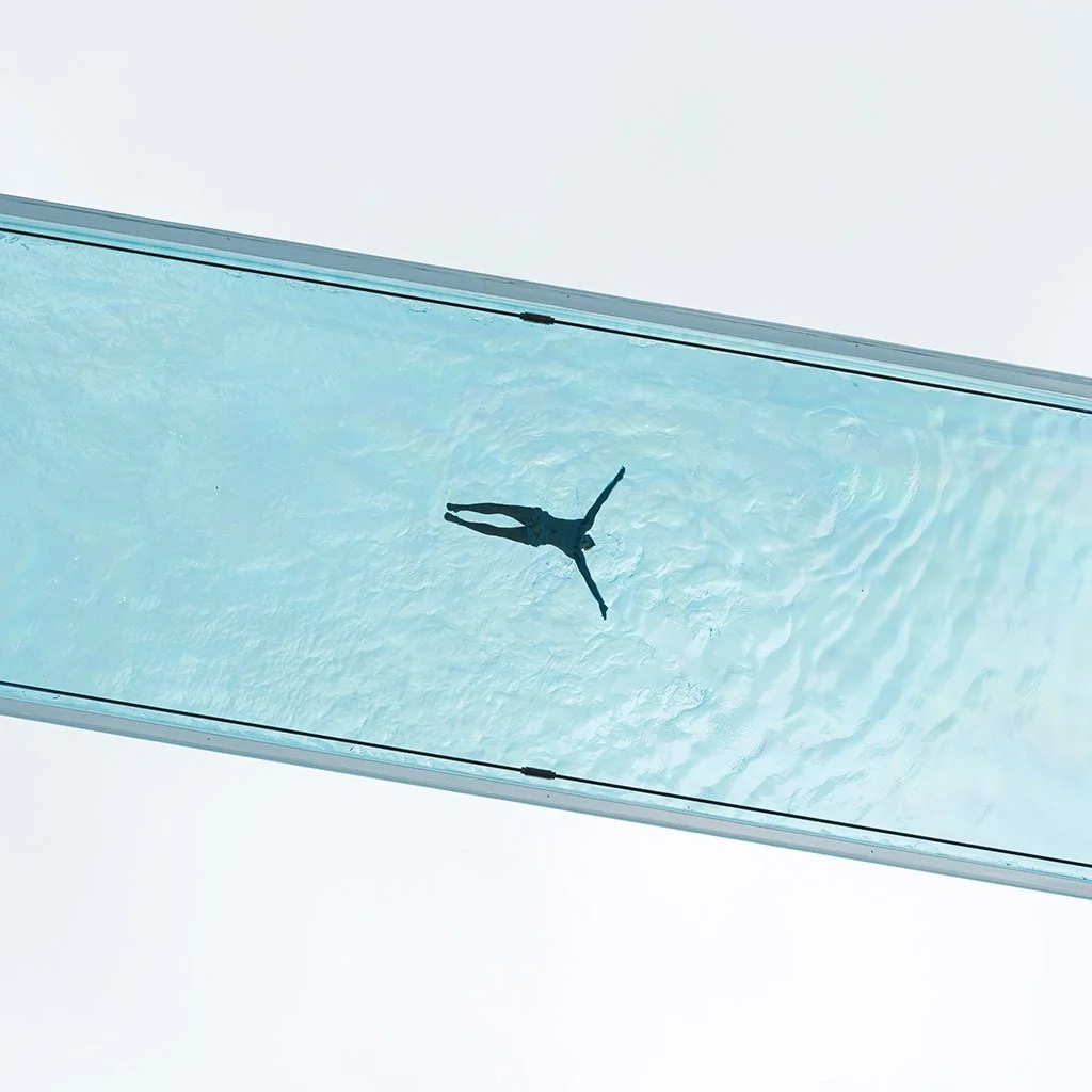 minimalist photo looking up at a swimming pool clear bottom swimmer in the middle