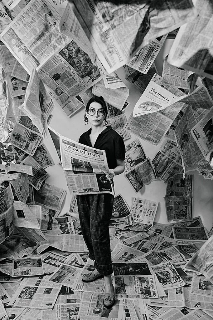Woman holding a newspaper amidst a cluttered background