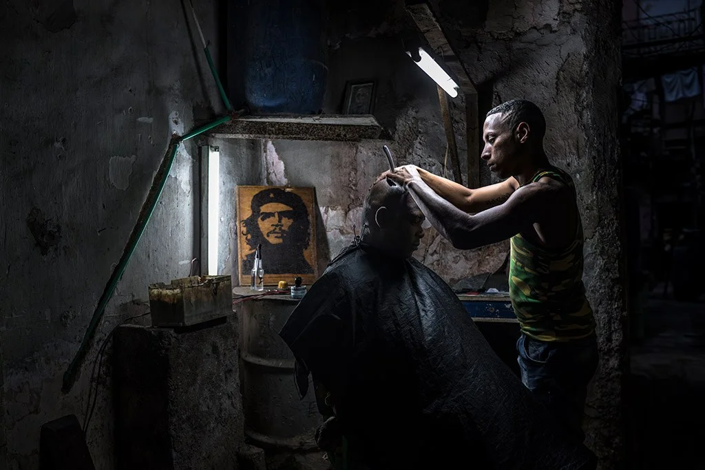 Barber and client in a dimly lit environment