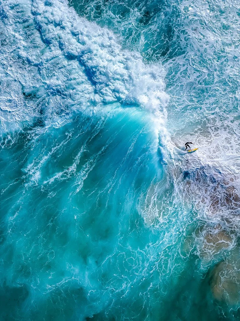Drone shot over waves crashing around a surfer, APOY 2024 action winner